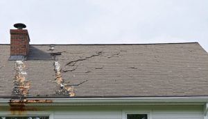 Damaged roof with visible cracks and peeling shingles, highlighting common roof issues relevant to new homeowners in New Jersey.