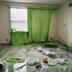Room with green mold growth on walls and floor, debris scattered, highlighting the aftermath of HVAC failure and the need for mold prevention and remediation.