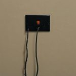 Electrical outlet with exposed wires, highlighting potential wiring hazards in older homes.